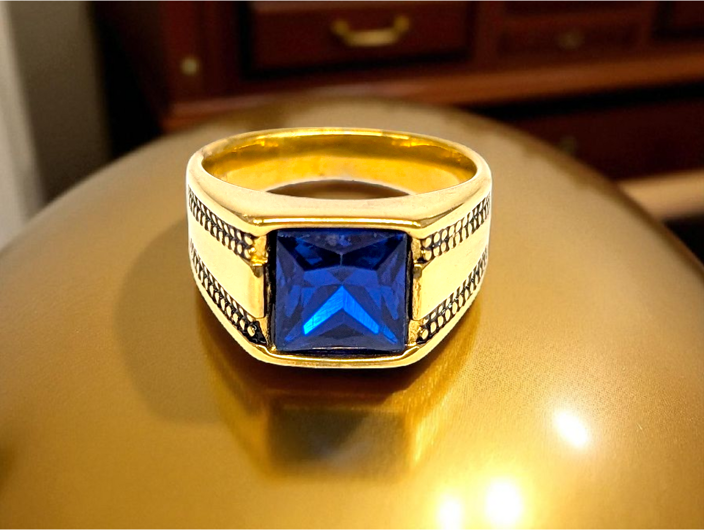 Regal Depth: Gold Ring with Blue Gemstone & Black Accents